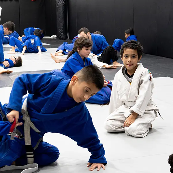 Kids in blue and white gis training Brazilian Jiu-Jitsu on the mats at Trillium MMA